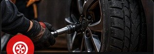 Technician removing wheel lugs for flat tire help